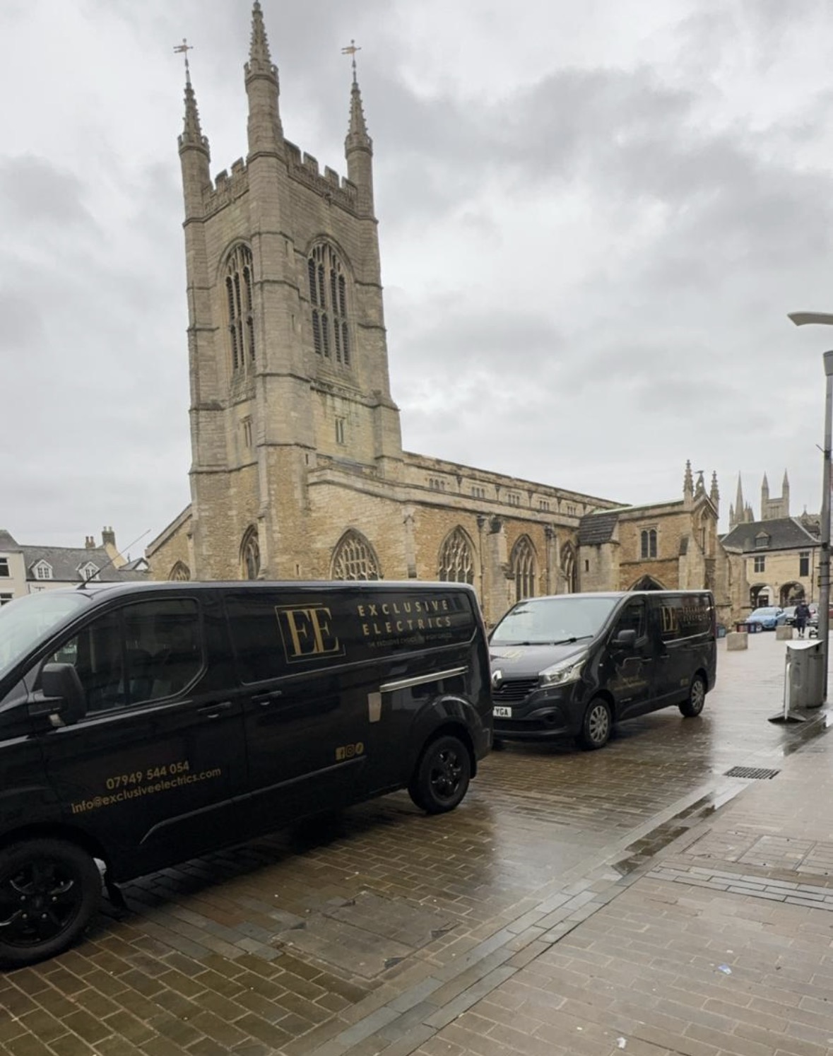 Two black Exclusive Electrics vans parked on Cathedral Square in Peterborough