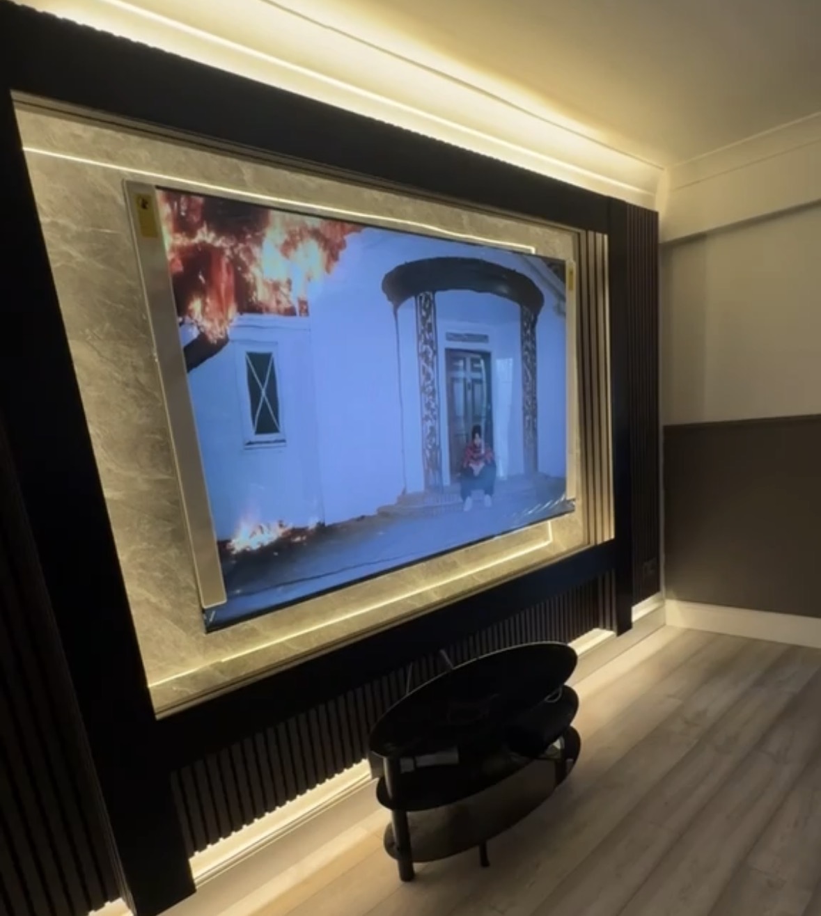 Television set into a marble-effect panel framed by concealed warm LED lighting with fluted wall panelling