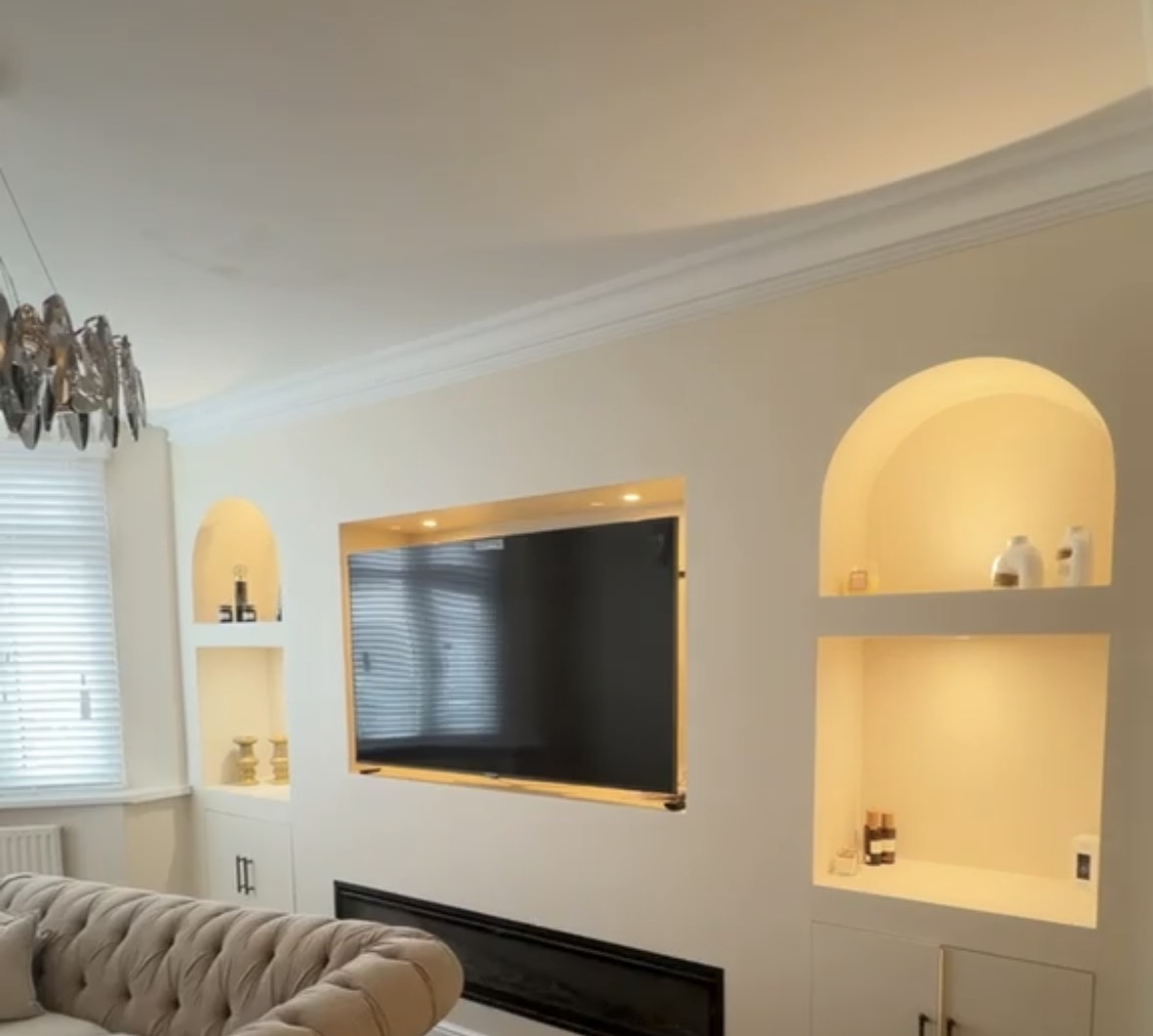 Arched display alcoves and a recessed TV surround finished with concealed warm LED lighting