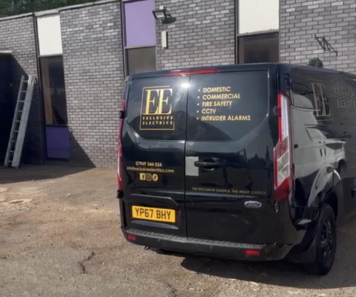 Rear of an Exclusive Electrics van listing domestic, commercial, fire safety, CCTV and intruder alarm services