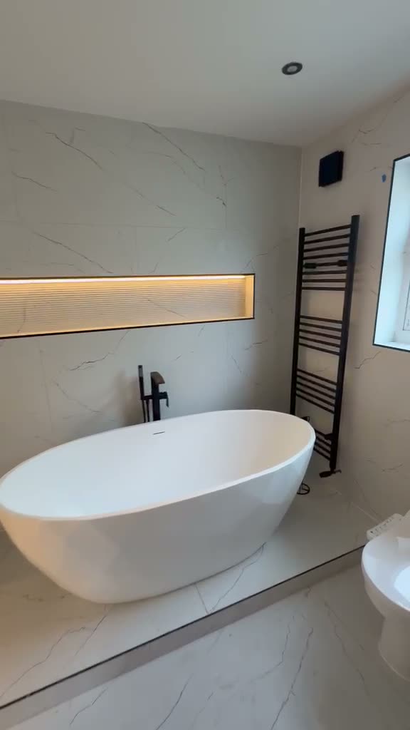 Walkthrough of a finished bathroom with an illuminated tiled niche and integrated mirror lighting